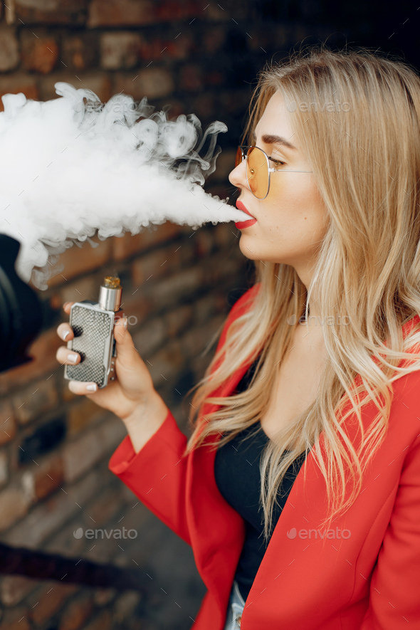 Stylish young girl in a city with vape Stock Photo by prostooleh